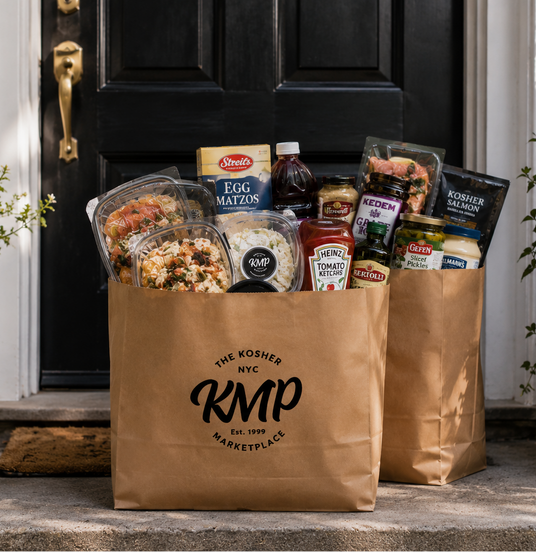 Two brown paper bags from The Kosher KMP Marketplace filled with groceries on a doorstep.
